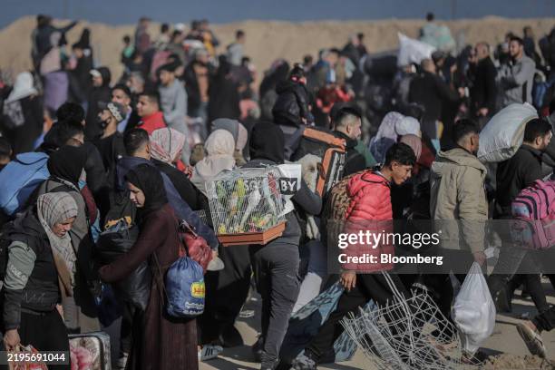 Man carries a cage of parakeets as he joins thousands of displaced Palestinians walking towards their homes in northern Gaza via the Netzarim...