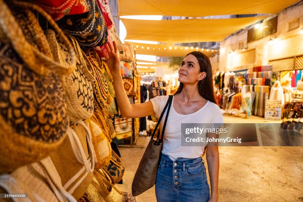Mid adult female tourist looking at bags in Dubai souk