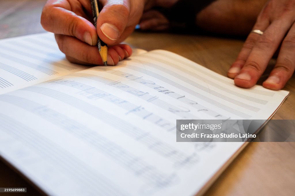 Close-up of a man writing music notes at note pad