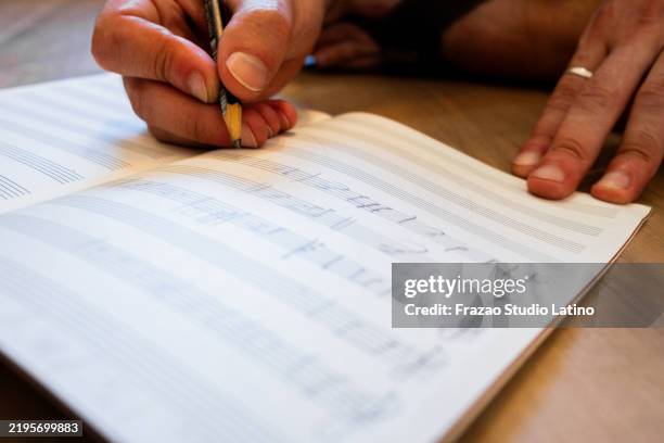 close-up of a man writing music notes at note pad - componist stockfoto's en -beelden