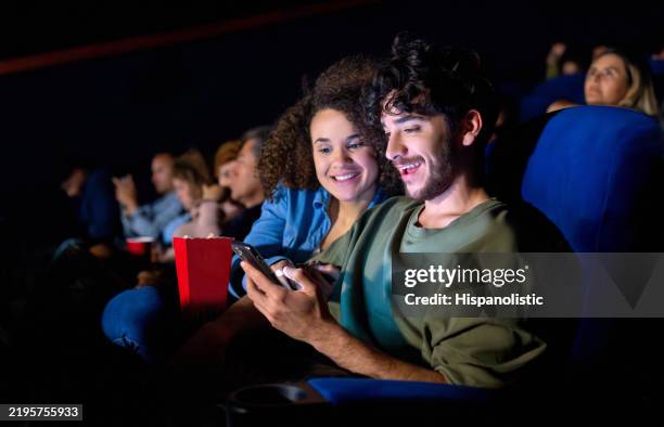pareja usando su teléfono celular en el cine - grupo mediano de personas fotografías e imágenes de stock