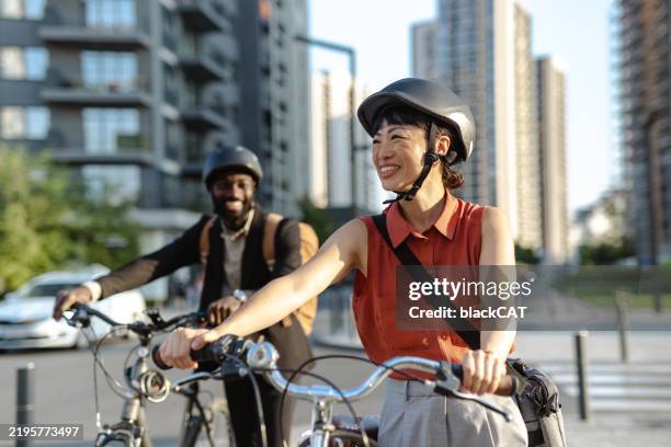 deux amis profitent d’une balade à vélo dans un cadre urbain moderne - casque de protection au sport photos et images de collection