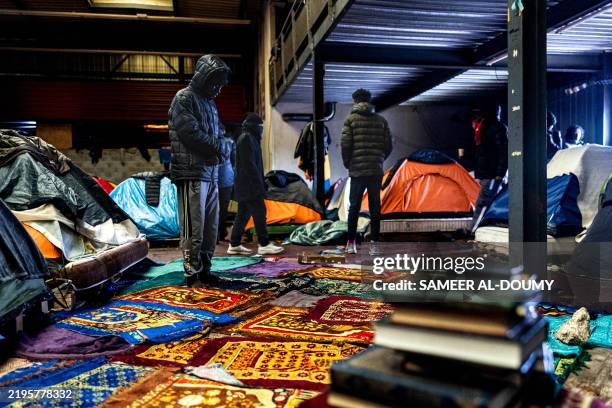 TOPSHOT - A migrant prays inside a warehouse in Marck, near Calais, northern France on January 24, 2025. In the industrial zone of Calais, hundreds...