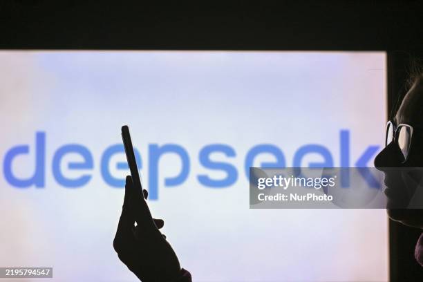 Woman holds a cell phone in front of a computer screen displaying the DeepSeek logo, on January 28 in Edmonton, Canada.