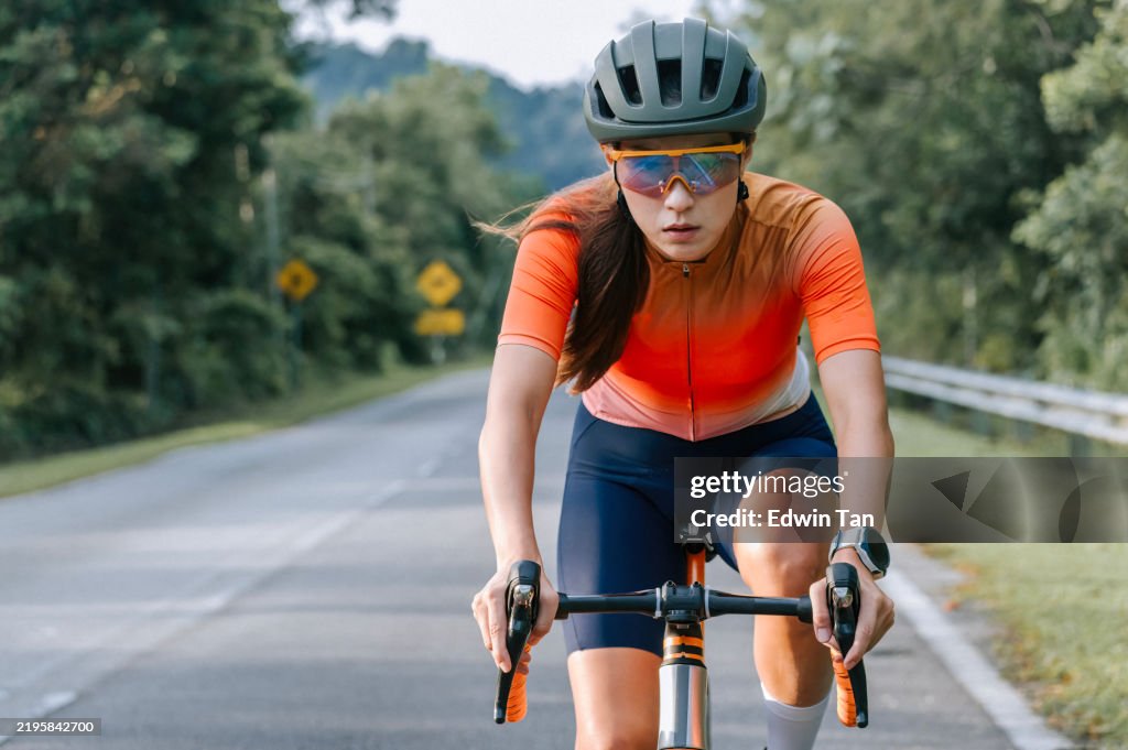 アジアの中国人スポーツウーマンサイクリング。スポーティフィットの女性乗馬ロードバイクでロードエクササイズ。ワークアウトやトレーニング中の持久力と有酸素運動
