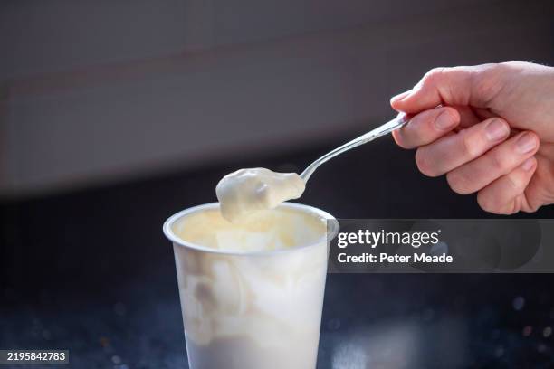 eating yoghurt out of a plastic yoghurt pot - yoghurt stock pictures, royalty-free photos & images