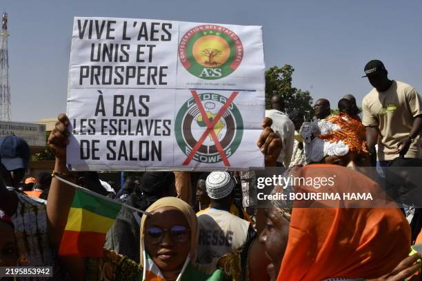 Woman holds a sign in support of the Alliance of Sahel States during a gathering to celebrate the withdrawal of Mali, Niger and Burkina Faso from the...