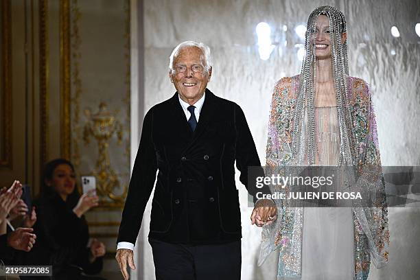 Italian designer Giorgio Armani acknowledges the applause with Latvian model Agnes Zogla at the end of his presentation for Armani Prive during the...