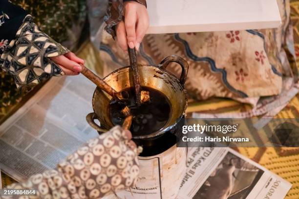 three friends dipping canting into hot wax for batik - social history stock pictures, royalty-free photos & images