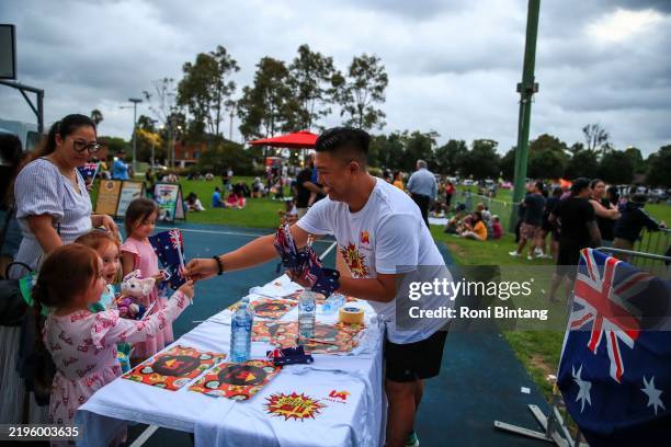 Man distributes free mini Australian flags during the Australia Day celebrations at Adams Park Canley Vale on January 26, 2025 in Sydney, Australia....