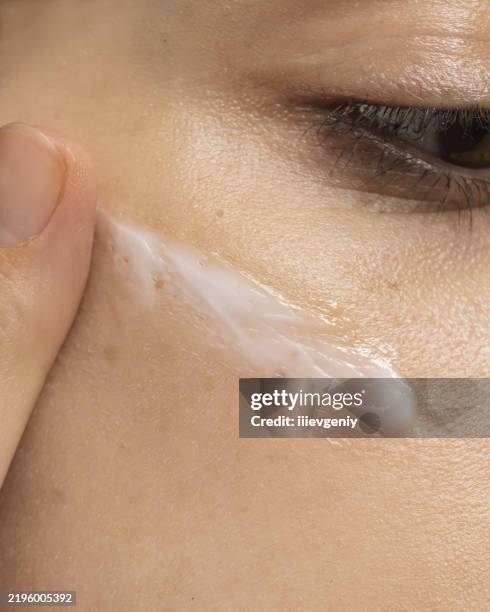 creme auf das gesicht. hautpflege - trockene augen stock-fotos und bilder