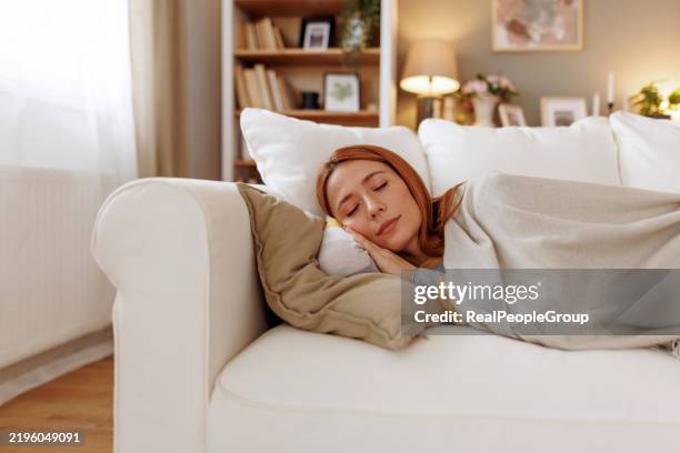 serene woman sleeping peacefully on a comfortable sofa at home - napping stock pictures, royalty-free photos & images
