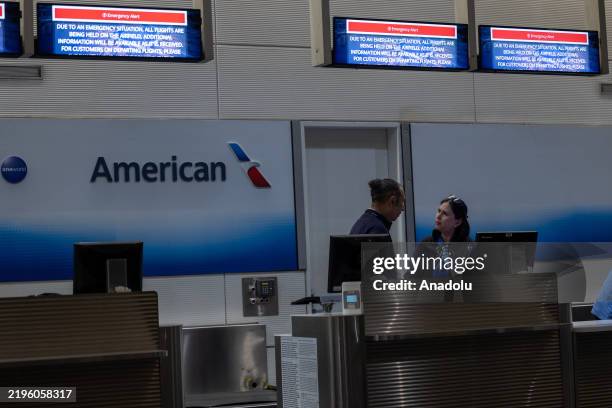 Staff are seen behind the American Airlines check-in desk inside Ronald Reagan National Airport as signage displays an emergency message, following a...