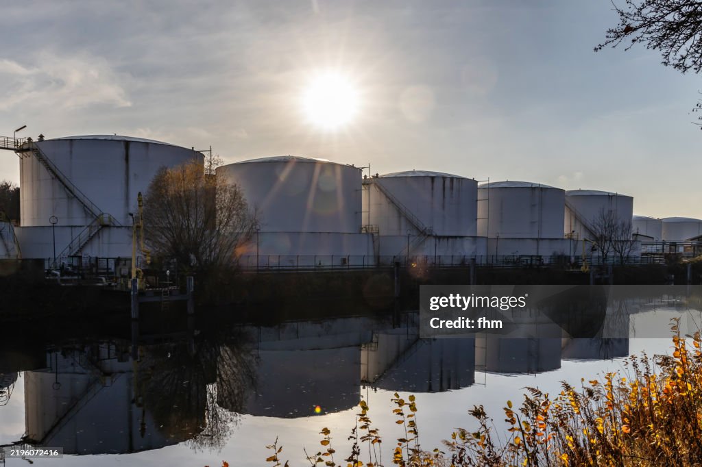 Large fuel storages next to a river with bright sun