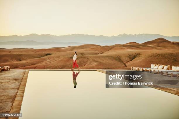 extreme wide shot woman walking poolside at luxury desert camp - travel stock pictures, royalty-free photos & images