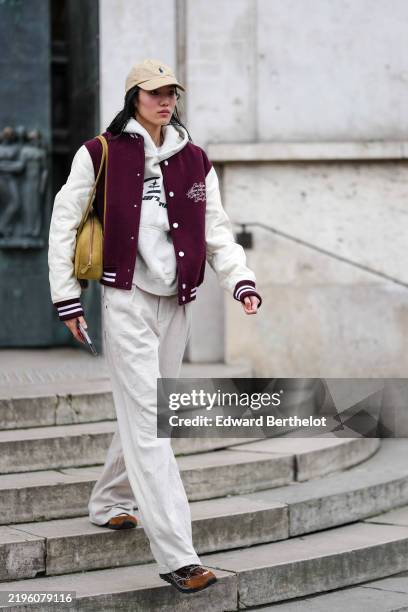 Model wears light brown Polo Ralph Lauren baseball cap hat, white oversized hoodie, burgundy bordeaux letterman, yellow green leather bag, white...