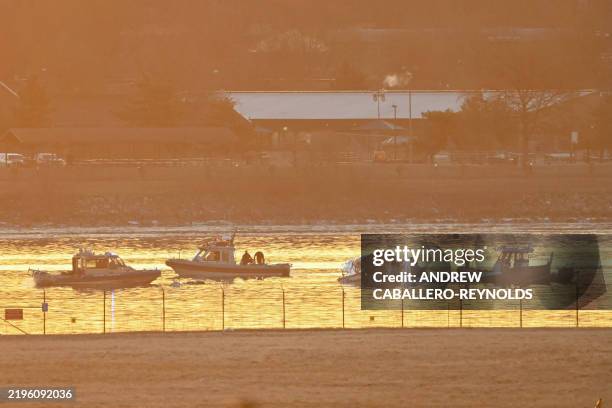 Part of the wreckage is seen as rescue boats search the waters of the Potomac River after a plane on approach to Reagan National Airport crashed into...