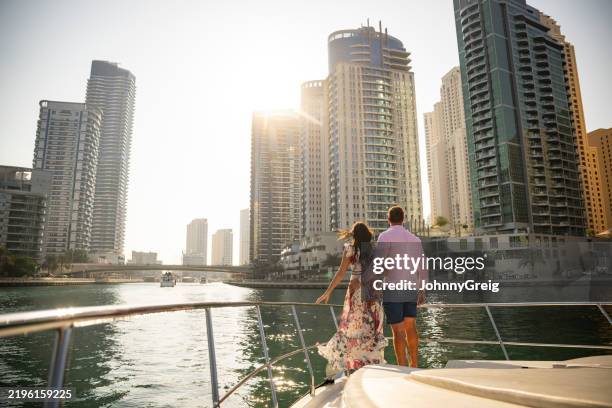 mittleres erwachsenen-expatriate-paar, das auf einer luxusyacht steht und die aussicht auf dubai genießt - dubai stock-fotos und bilder