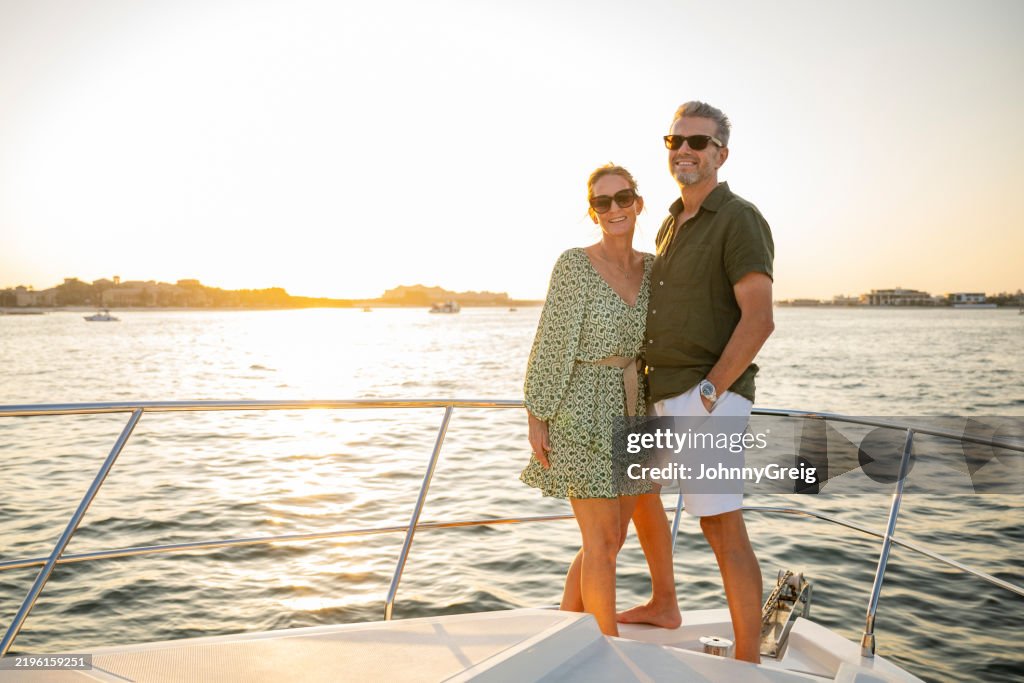 Mature couple in their 50s smiling towards camera on luxury yacht