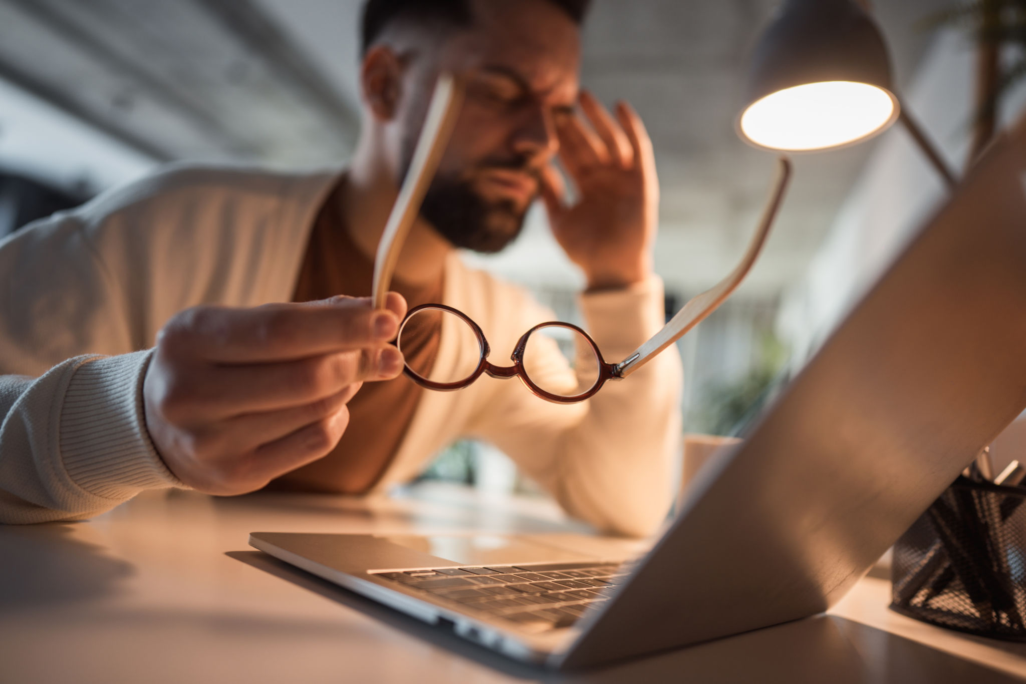 Man working remotely, overwhelmed by fatigue and a headache Man working remotely, overwhelmed by fatigue and a headache