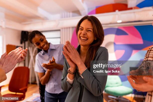 femme d’affaires excitée riant et applaudissant avec ses collègues au bureau - applaudir photos et images de collection