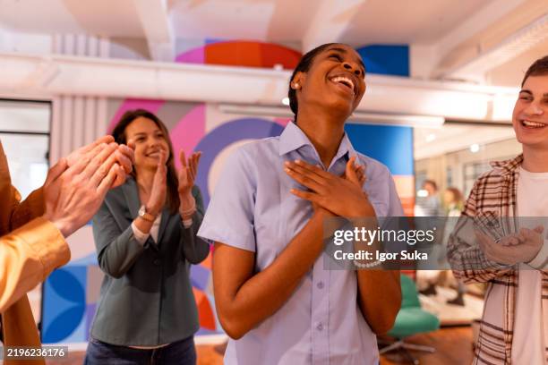grateful employee receiving applause from colleagues in modern office - bewondering stockfoto's en -beelden