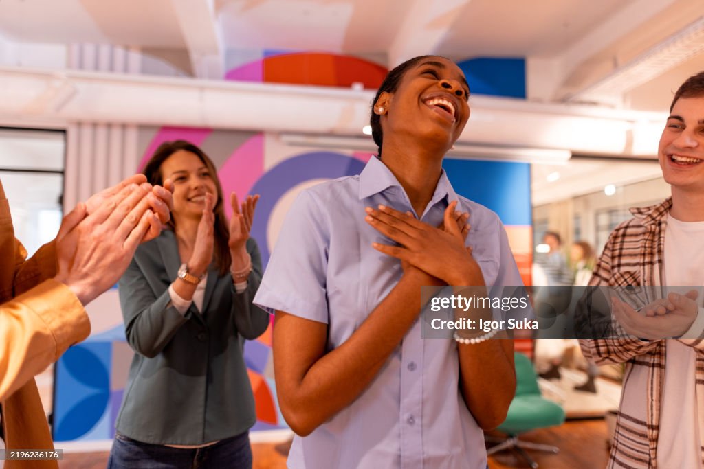 Grateful employee receiving applause from colleagues in modern office