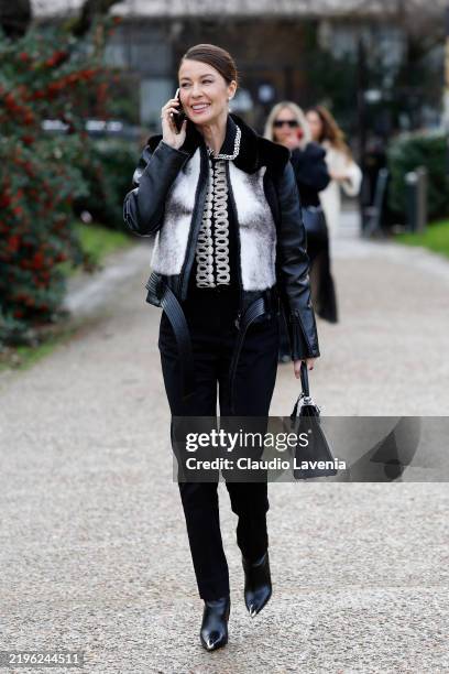 Guest wears black jacket with white fur details, black trousers, black boots and bag, outside Georges Hobeika, during Haute Couture Spring-Summer...