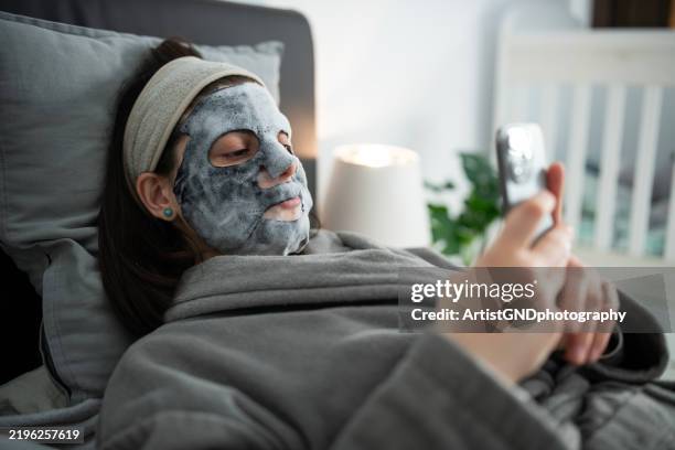 relaxing at home with a sheet face mask. - wearing cloth face mask stock pictures, royalty-free photos & images