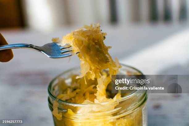 fork lifting sauerkraut from a jar in sunlight - sauerkraut stock pictures, royalty-free photos & images