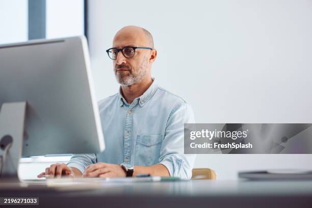 uomo professionale focalizzato che lavora al computer in moderno ambiente d'ufficio - ergonomia foto e immagini stock