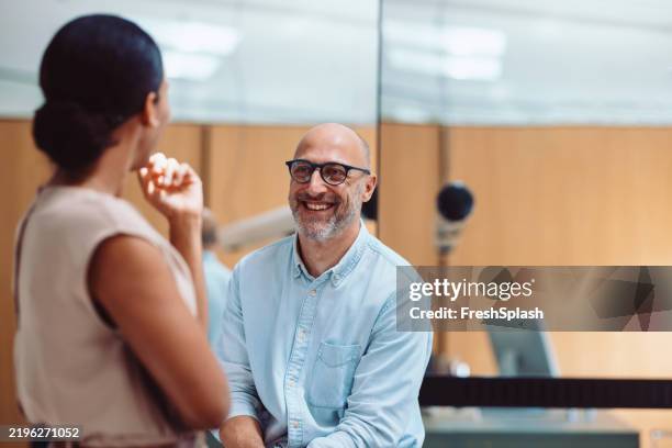 happy colleagues chatting in the office during a friendly interaction - face-to-face stock pictures, royalty-free photos & images