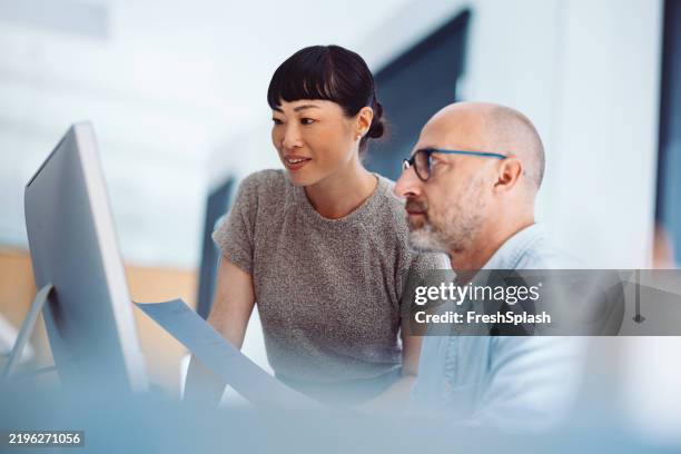 team members collaborating over a project in an office environment - asian man looking away stock pictures, royalty-free photos & images