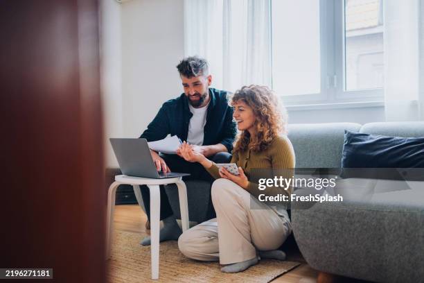 couple collaborating on financial planning at home using laptop and documents - mid adult couple stock pictures, royalty-free photos & images