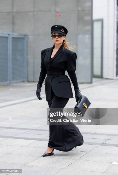 Merve Görgöz wears black flat cap hat, tailored blazer, bag, gloves, skirt outside Rahul Mishra during Haute Couture Spring-Summer 2025 as part of...