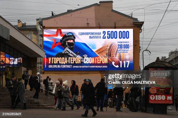 Pedestrians walk past a digital billboard promoting contract army service with the slogan "Hero City has its heroes" in Saint Petersburg, on January...