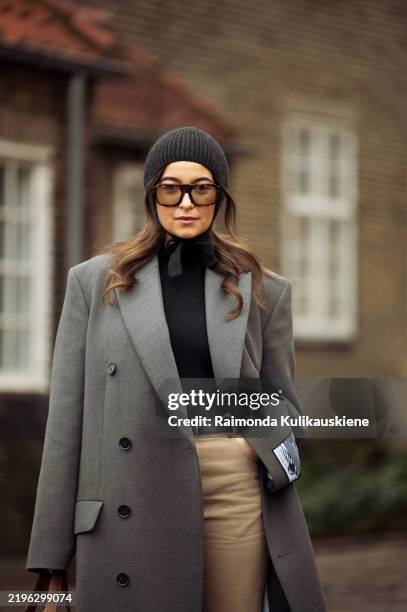 Benthe Liem wears beige pants, black turtle neck, grey coat and dark grey knitted hat outside the OpéraSport show during the Copenhagen Fashion Week...