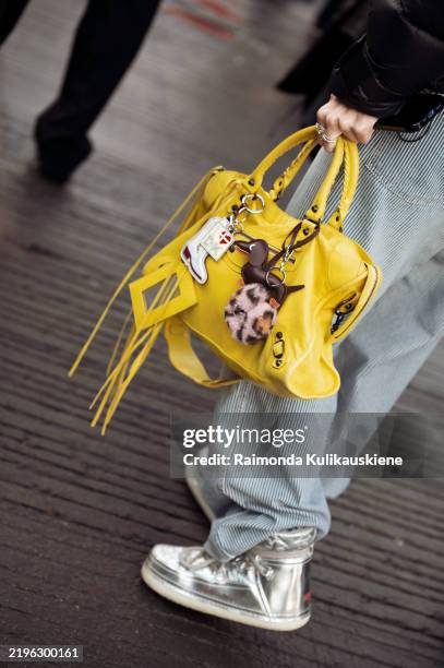Guest wears blue jeans and yellow bag with accessories outside the Forza Collective show during the Copenhagen Fashion Week Autumn/Winter 2025 on...