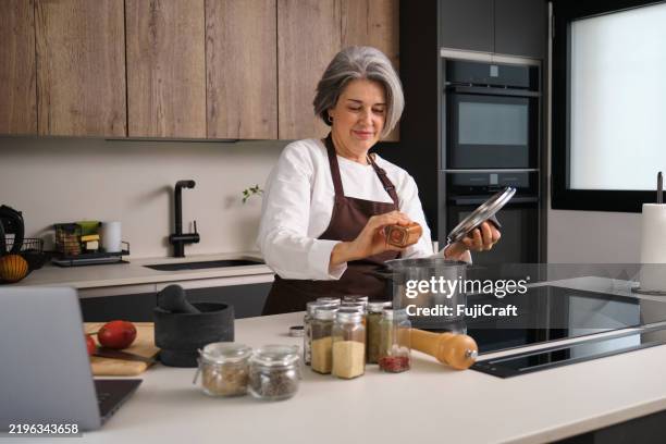 chef adding spices while cooking following online recipe on laptop computer - adding spice stock pictures, royalty-free photos & images