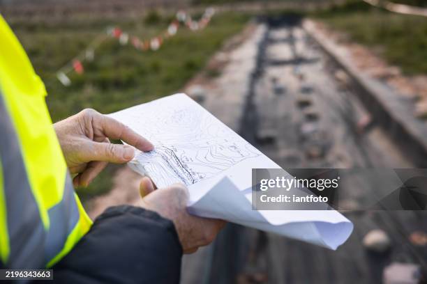 primer plano de un arqueólogo trabajando en un sitio arqueológico mirando un mapa topográfico. - arqueología fotografías e imágenes de stock