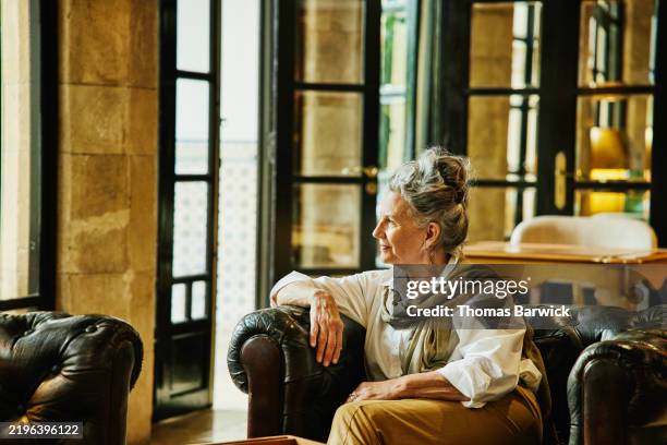medium wide shot senior woman relaxing in lounge of luxury hotel - richesse photos et images de collection