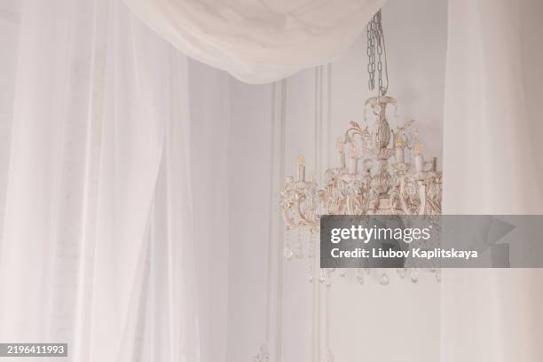 elegant vintage crystal chandelier against white wall - aristokratie stock-fotos und bilder