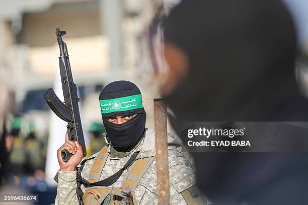 Palestinian militant group Hamas fighters secure an area before handing over two Israeli hostages to a Red Cross team in Khan Yunis on February 1 as...