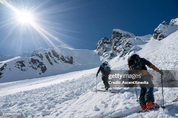 backcountry skiers cross avalanche slope - lawine stockfoto's en -beelden