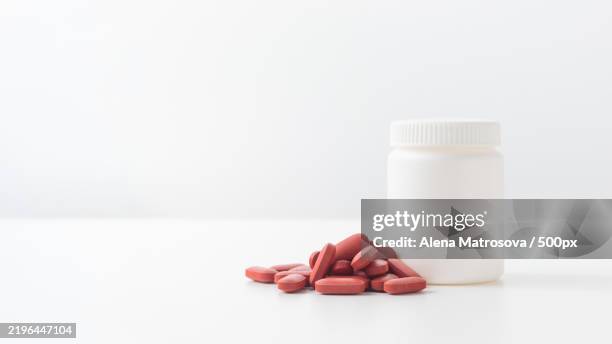 red pills and plastic medicine bottle on a white background with copy space medicine and health concepts include a jar with ferrum or iron pills or vitamin fe for treat iron deficiency anemia - iron deficiency anemia stock pictures, royalty-free photos & images
