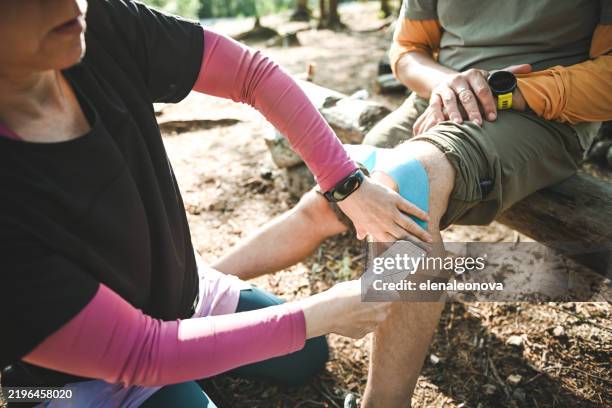 two hikers take a break at a forest camp, attending to a minor injury while surrounded by nature. - minor injury treatment photos et images de collection