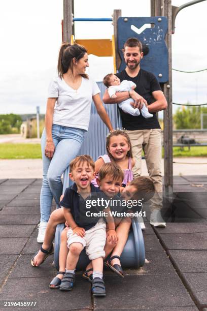 happy parents enjoying leisure time with kids playing on slide at playground - family with five children stock pictures, royalty-free photos & images