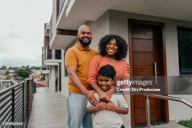 portrait of a happy family in front of their new home - homeowners insurance stock pictures, royalty-free photos & images