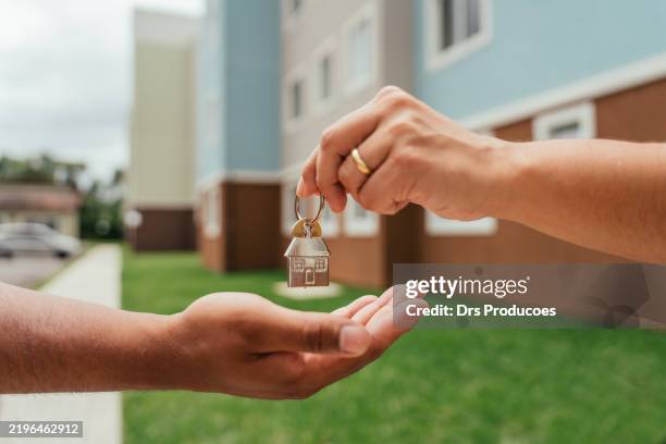 detail of real estate agent's hands handing over keys - housing development stock pictures, royalty-free photos & images