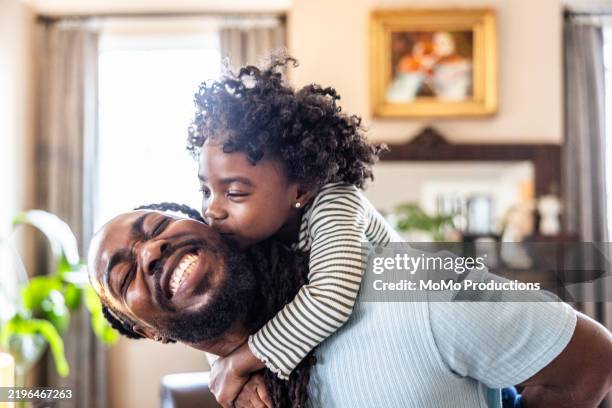 father giving young daughter a piggyback ride in living room - real life stock pictures, royalty-free photos & images